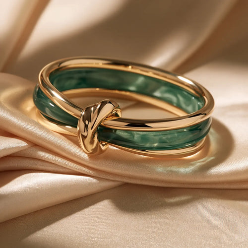 MAYA 01 Amalfi bangle in Malachite Gold, a marbled green band framed in polished gold with a sculpted gold knot, on champagne satin