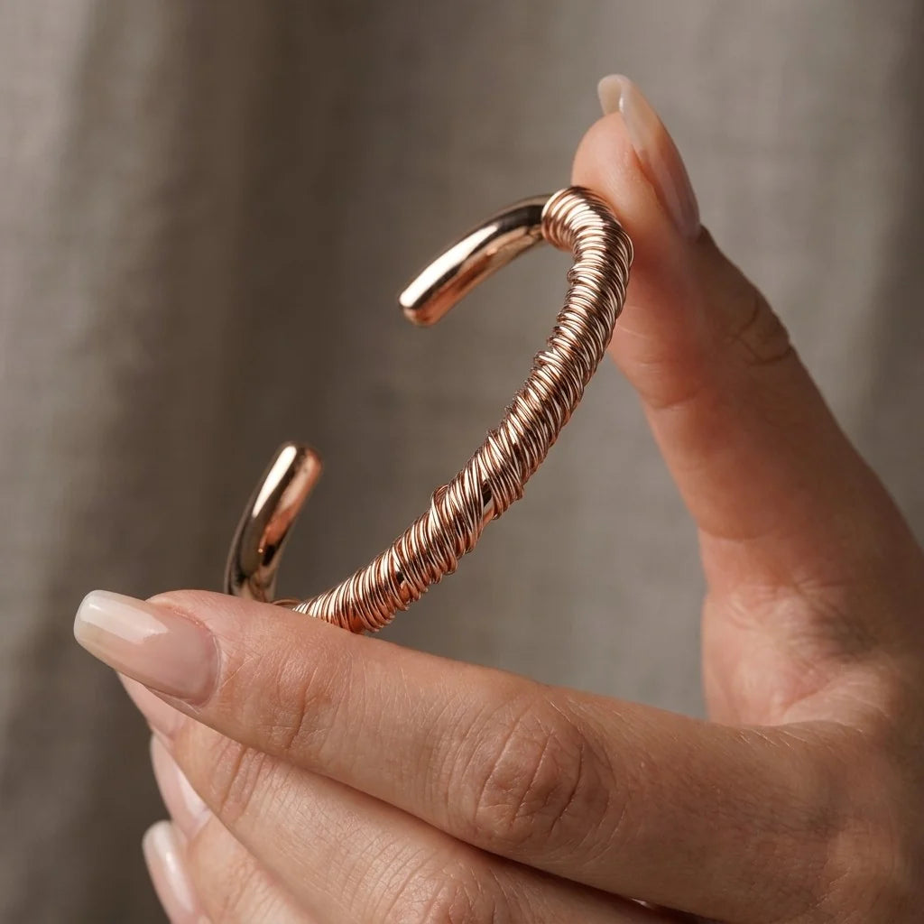 MAYA 01 Menton coiled cuff in Rose Gold held in the hand, showing the wire wrap and open ends