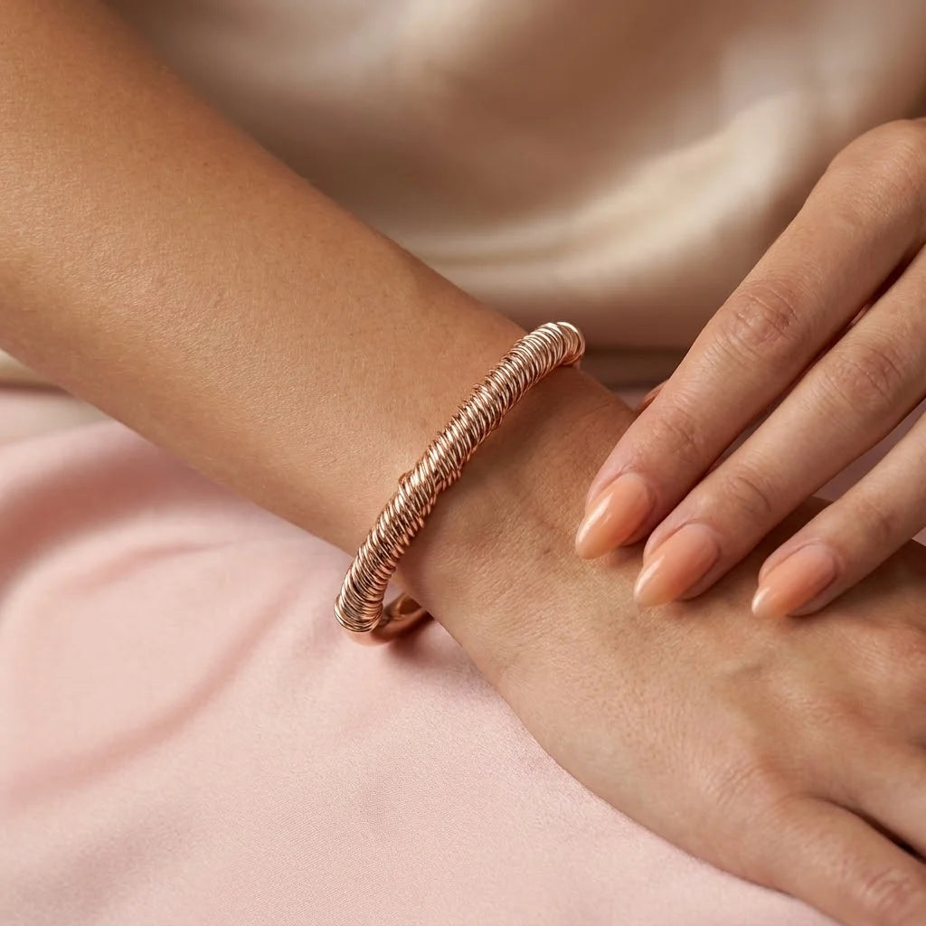 MAYA 01 Menton coiled cuff in Rose Gold worn on the wrist over blush satin
