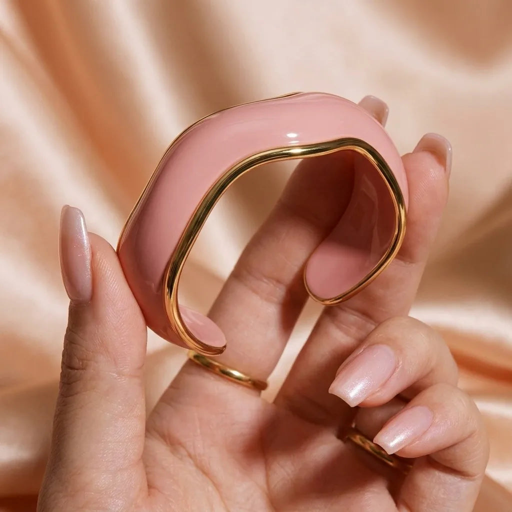 MAYA 01 Saint-Tropez wave cuff in Petal Pink held in the hand, showing the gold rim and open back