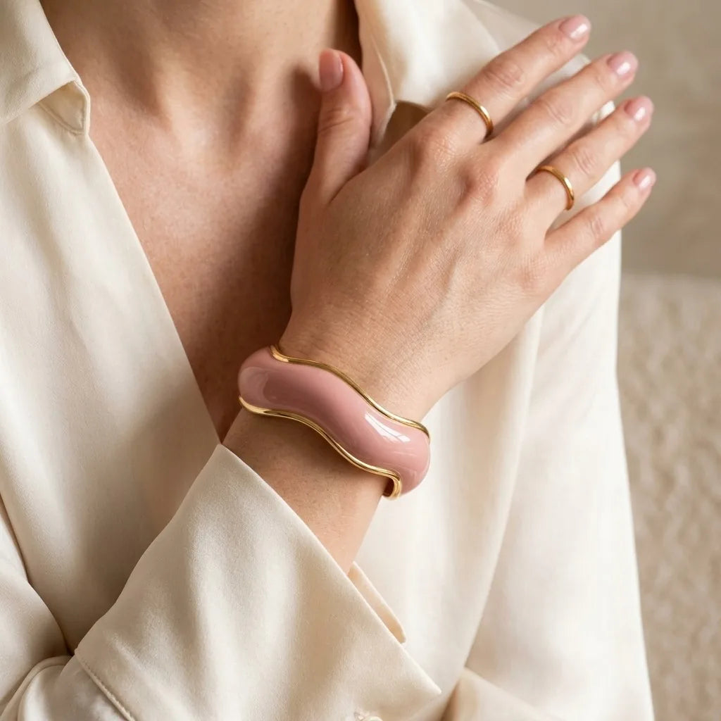 MAYA 01 Saint-Tropez wave cuff in Petal Pink worn with an ivory silk blouse and gold rings
