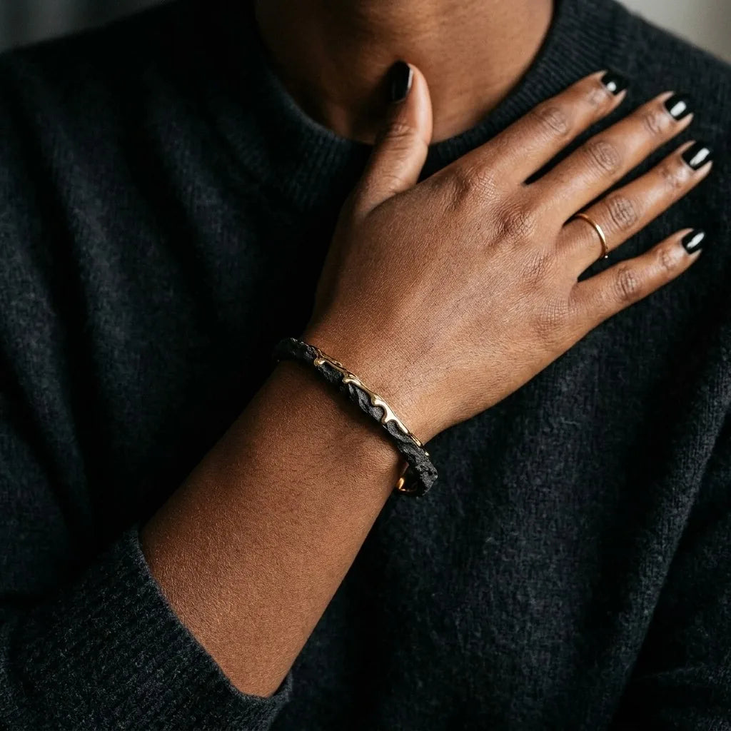 MAYA 01 Santorini cuff in Volcanic Gold worn with a charcoal knit sweater, hand resting at the chest