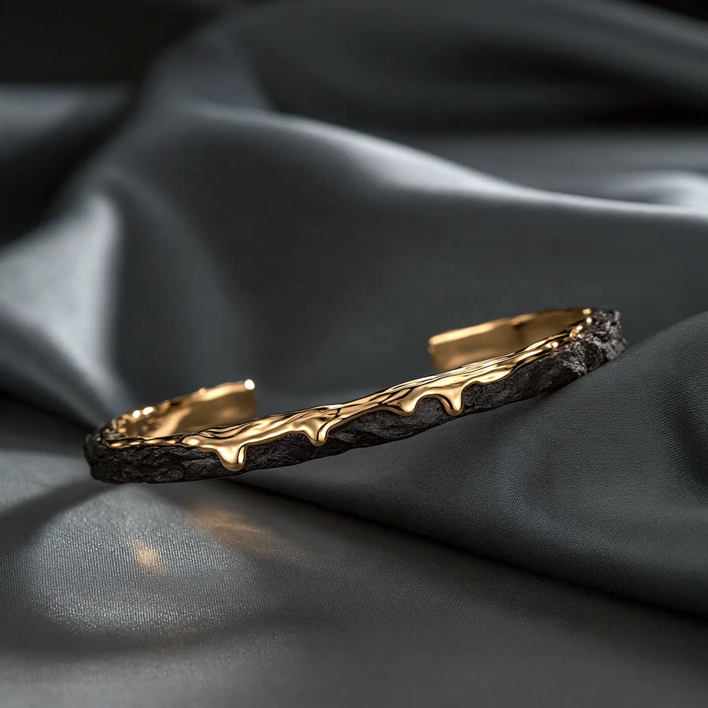 MAYA 01 Santorini slim open cuff in Volcanic Gold, textured matte black with molten gold drips along the edge, on charcoal satin