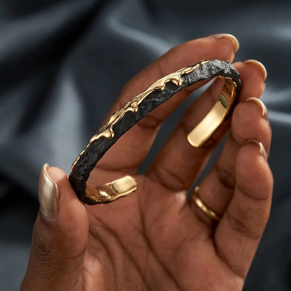 MAYA 01 Santorini cuff in Volcanic Gold held in the hand, showing the lava texture and polished gold inside