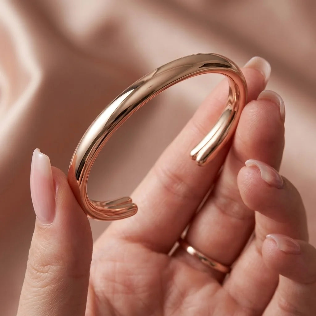 MAYA 01 Taormina cuff in Rose Gold held in the hand over blush satin, showing the split ends